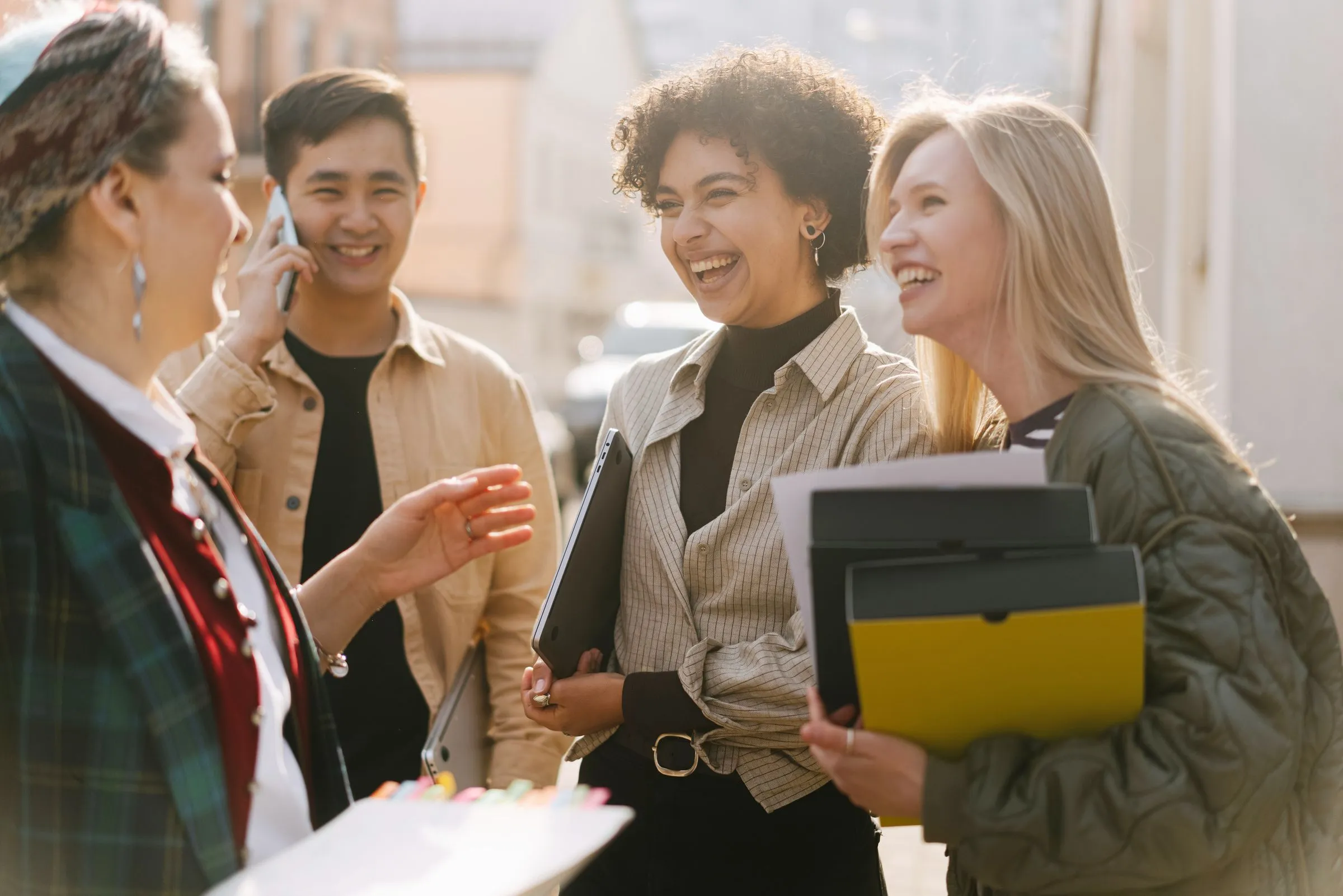 A diverse group of colleagues laughing together outdoors